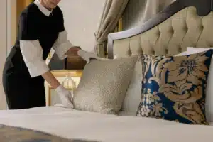 Hotel housekeeper fixing decorative pillows on a clean, well-prepared bed to make the guest room comfortable and organized