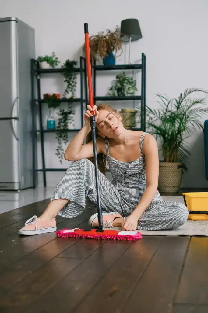 House cleaner resting on a mop after a long cleaning session