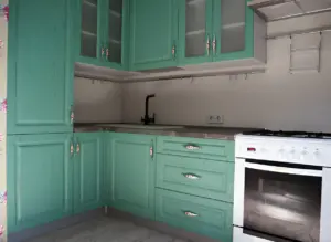 Close-up view of modern kitchen cabinets with a fresh green finish, showcasing a clean and organized space perfect for preparation before painting.